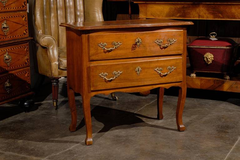 A petite French two-drawer commode from the early 19th century with curved legs. This French small size commode was born circa 1810 during the Napoleonic era. Below the serpentine top, the front features two drawers adorned with lovely hardware. The