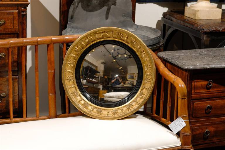 Ce miroir anglais de petite taille datant du début du XIXe siècle présente un cadre circulaire en bois doré entourant un miroir convexe. Le motif du cadre présente une alternance de motifs floraux. À l'intérieur du cadre en bois doré de ce miroir