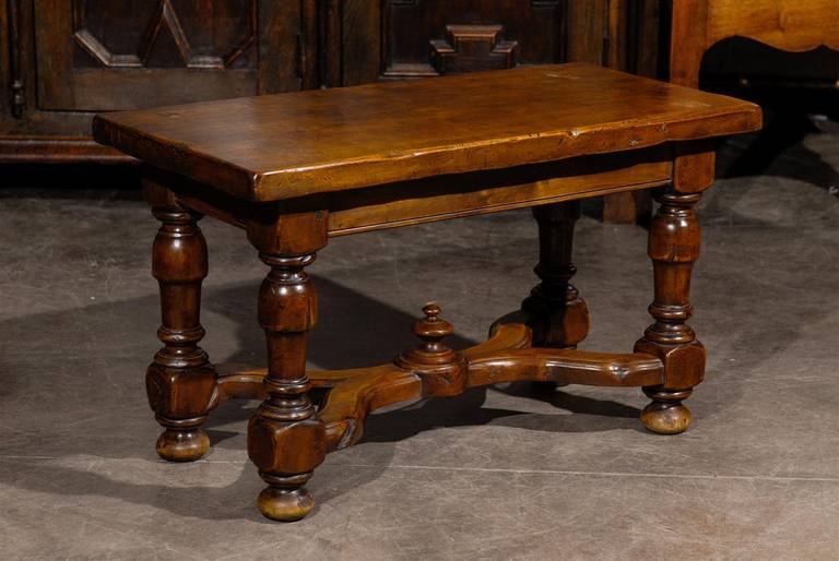 A French walnut stool or bench. This French small size wooden bench features a rectangular top sitting over four beautifully turned legs with bun feet. The x-shaped cross stretcher is adorned with a circular carved motif in its centre. The nice