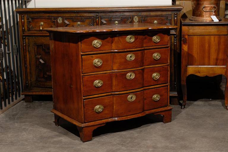 A late 18th century Italian fruitwood commode with serpentine front. This Italian chest of drawers from circa 1790-1810 features a rectangular top, curved in the front, nicely following the shape of the recessed serpentine front below. The front of