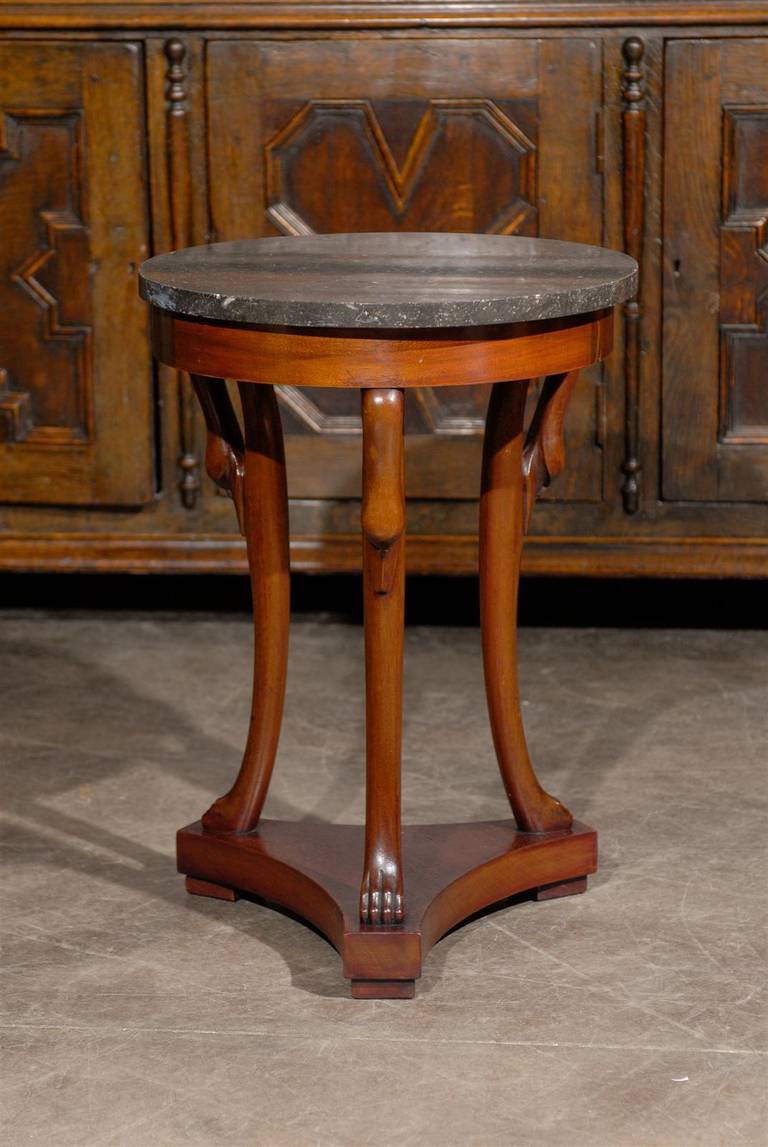 A French Directoire style late 19th century table with three legs and a marble top. This French guéridon side table features a circular grey marble top supported by three exquisitely carved legs, adorned in their upper section with swan head motifs