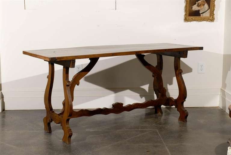 A Spanish Baroque style walnut table with rectangular top and stretcher from the second half of the 19th century. This Spanish side table features a two plank rectangular top sitting on trestle base with exquisite lyre-shaped legs. The slightly