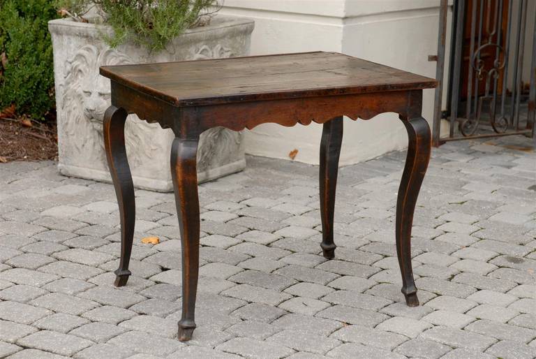 This French oak Louis XV style rustic table from the late 19th century features a rectangular four-plank top over a nicely scalloped apron on all sides. The table is raised on four cabriole legs with hoof feet. This French side table from the 1890s
