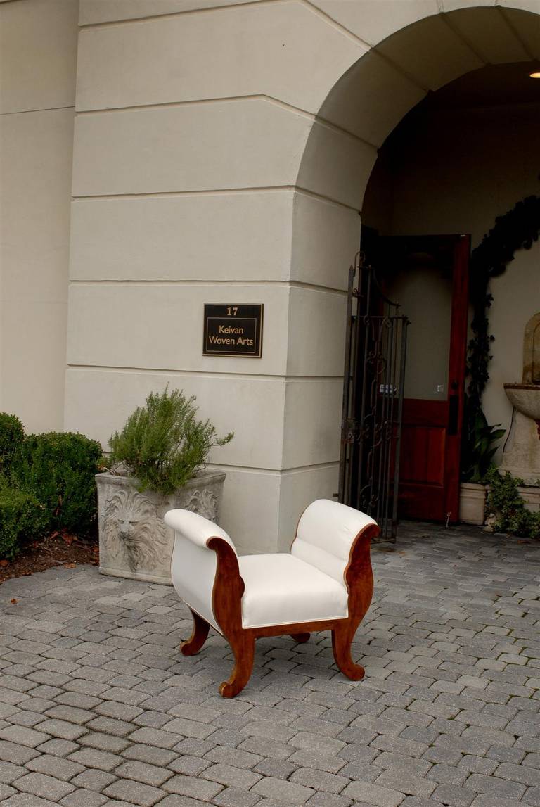 This adorable Austrian Biedermeier walnut stool from the mid-19th century features high out-scrolled upholstered arms flanking an upholstered seat. The simple curvy lines of the upper section are reprised in the base, with the four scrolled feet.