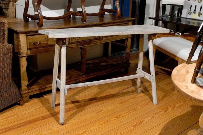 This French painted work table, called “table de lavandière” in French is from the early part of the 20th century. The single plank top sits on a simple trestle base made of four splayed legs connected to one another with a cross stretcher.  This