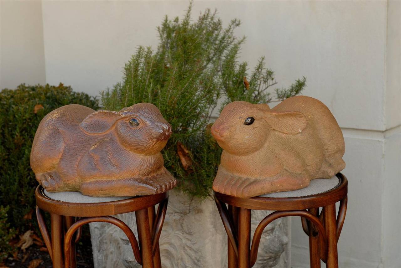 Paire de sculptures de lapins en terre cuite peinte du milieu du siècle dernier, Angleterre. Chaque lapin affiche une posture vivante et agréable, reposant sur ses pattes avant avec les oreilles en arrière. Les poils sont sculptés avec un grand