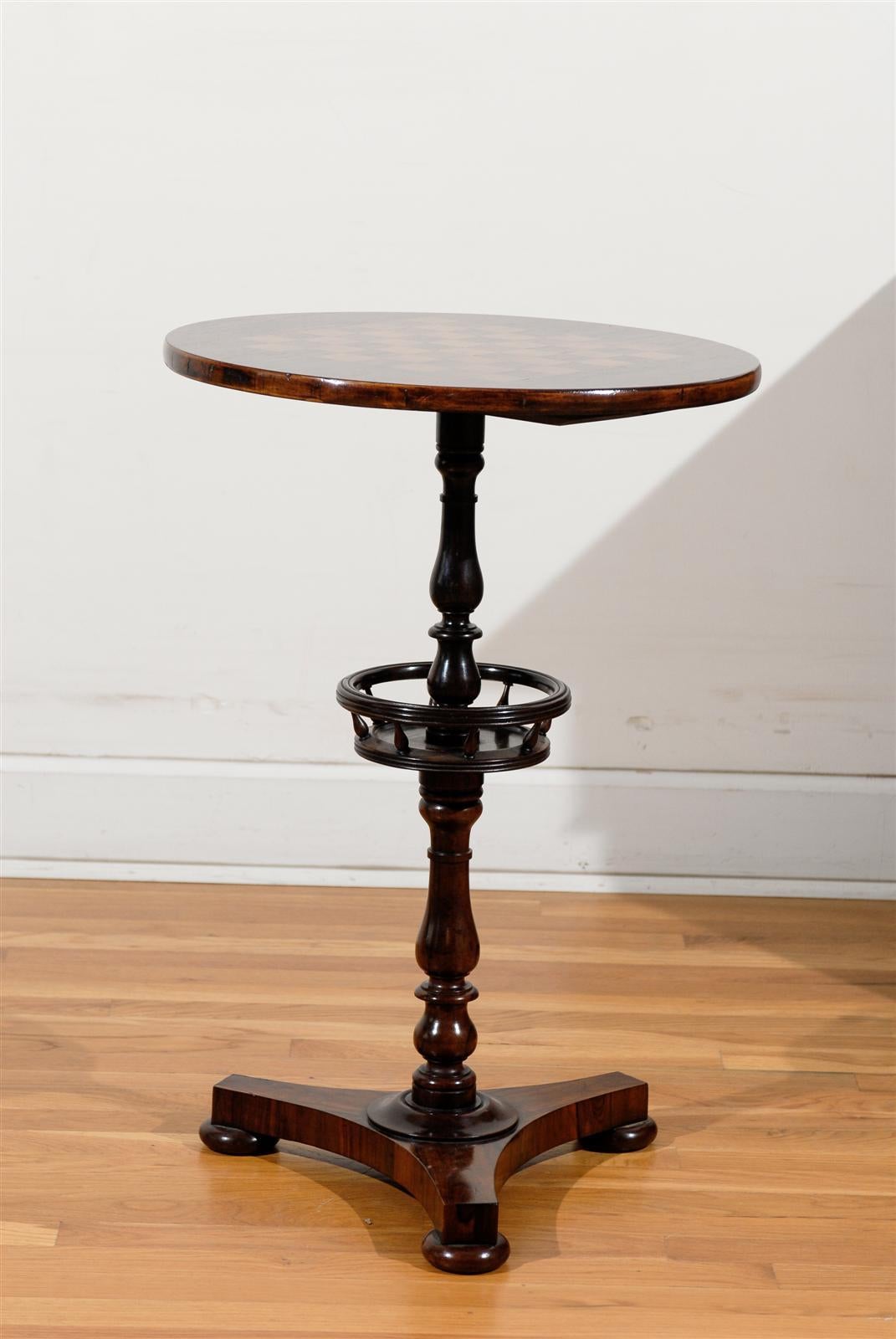 An English rosewood games table with checkerboard inlaid top and pedestal base from the second half of the 19th century. This English gueridon side table features a circular top, exquisitely adorned with an inlaid checkerboard. The table is raised