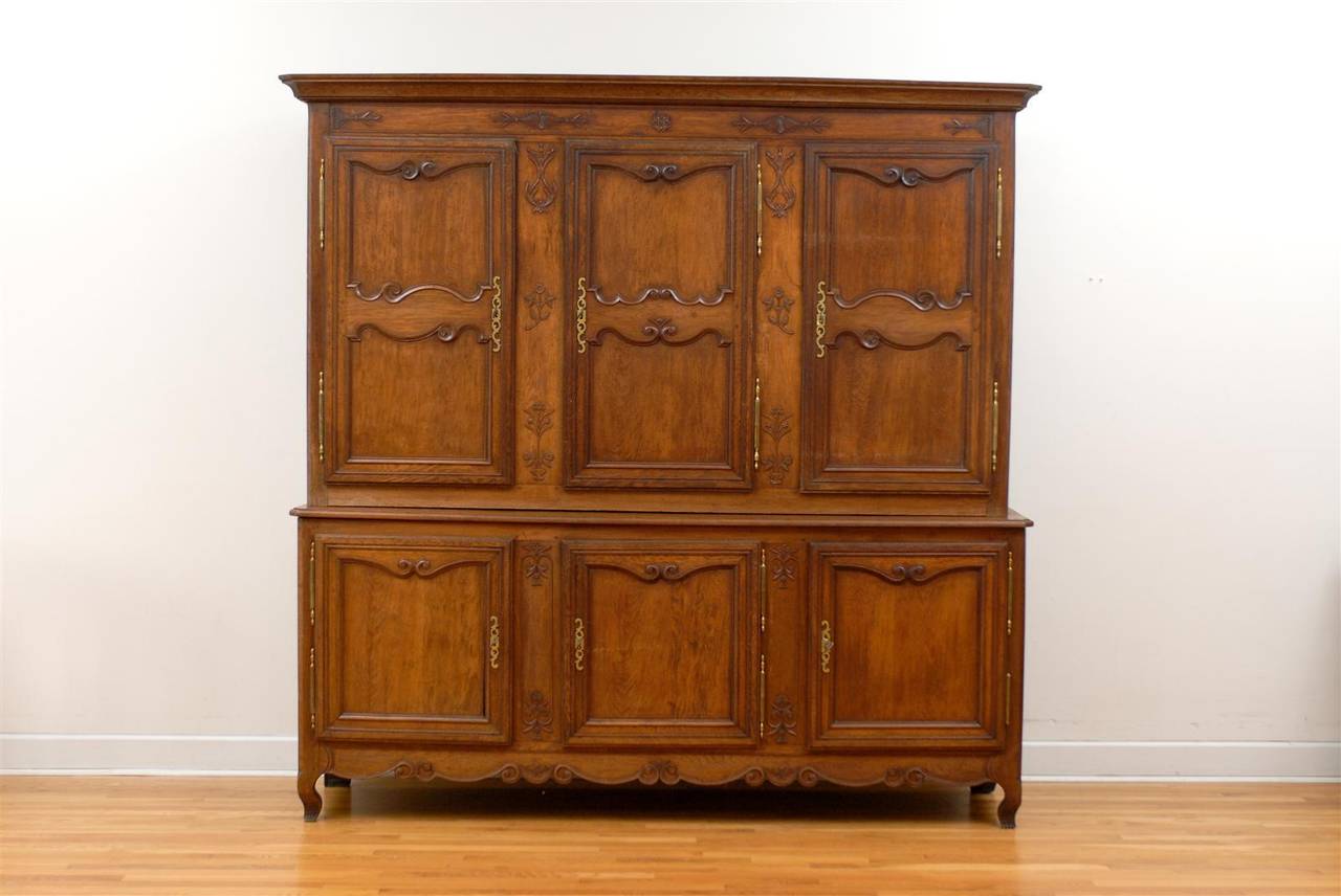 A French large wooden two-part cabinet with six doors, carved panels and scalloped skirt from the early 19th century. This French cabinet was born in the early years of the 19th century, during the Restauration period, after the fall of Emperor