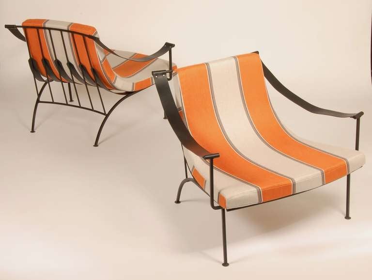 Dramatic iron lounges with leather arms and newly upholstered striped fabric. Curved back legs and flared accents on the back of the frame for both support and a striking visual element.