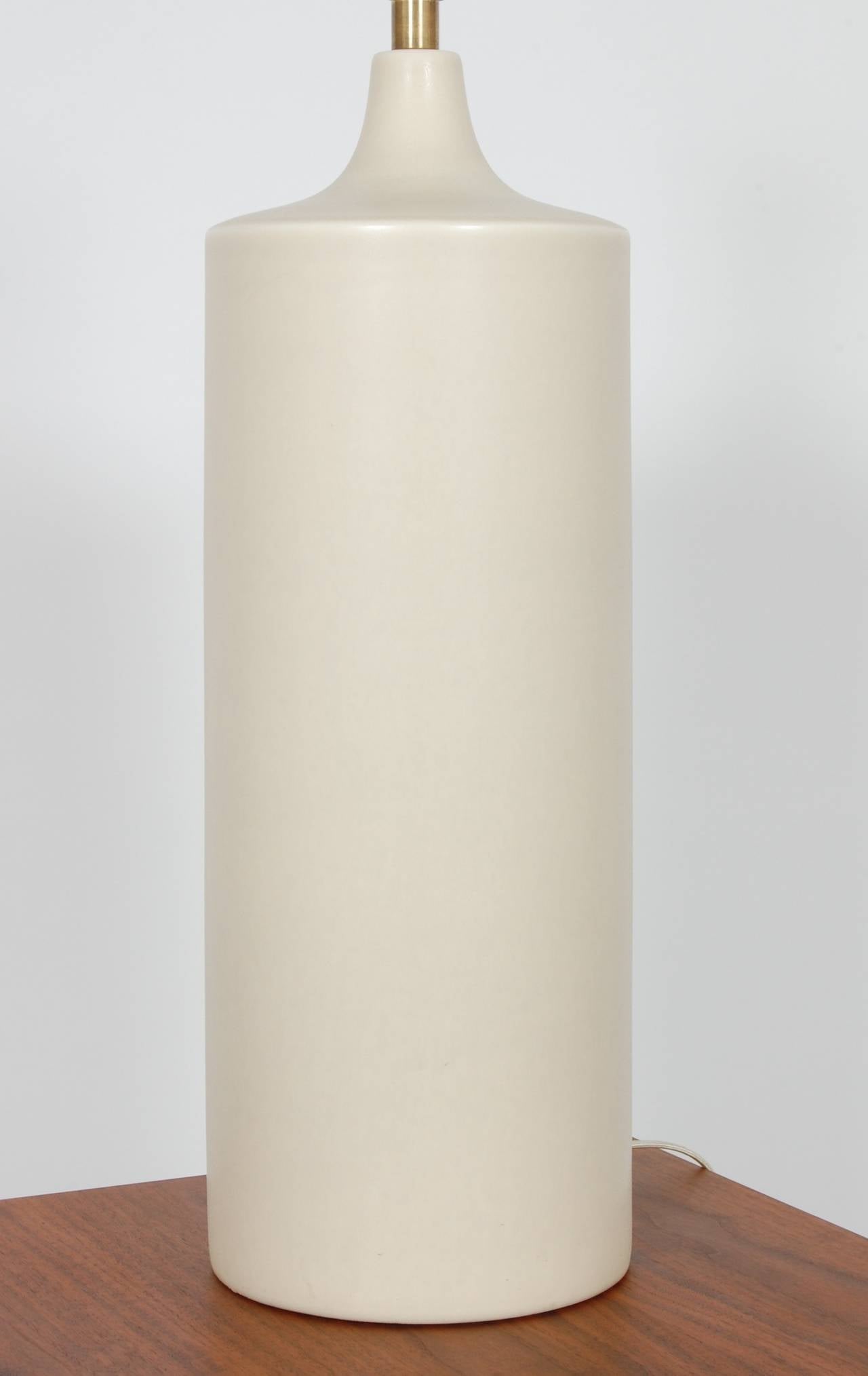 Large cylindrical form eggshell white ceramic lamp with a tapered top and brass accent, this lamp has been rewired. The height measurement is from base to the top of the socket.