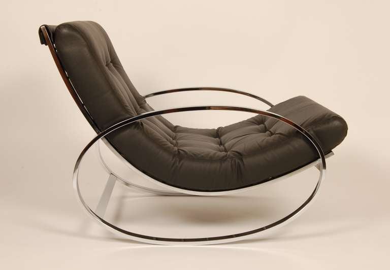 1970's era Selig rocker having a clever segueing oval armrest to leg design configuration. The tufted cushion conforms to the curved shape and is suspended by a series of vinyl coated spring cables running the entire back of the rocker.