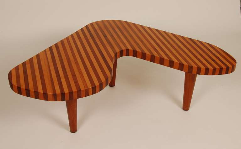 Freeform coffee table from brazil, constructed of solid strips of walnut and beech, laminated together and supported by conical teak legs. This table has a high attention of design and craft to it.