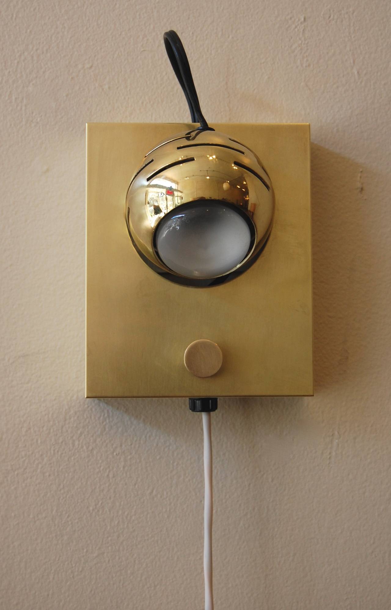 Arredoluce eye ball wall lamp crafted in brass, the ball head is held on by a magnet which allows for a large range of adjustments. The dimmer switch allows one to adjust the volume of light. This lamp has been hand polished, rewired and is labeled.