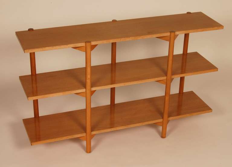 Three level shelf  designed by Milo Baughman for Glenn of California, circa 1950's. The three shelves are supported by five off set legs that are inset into each shelf. Additional design and aesthetic enhancement is the wedge block supports on the