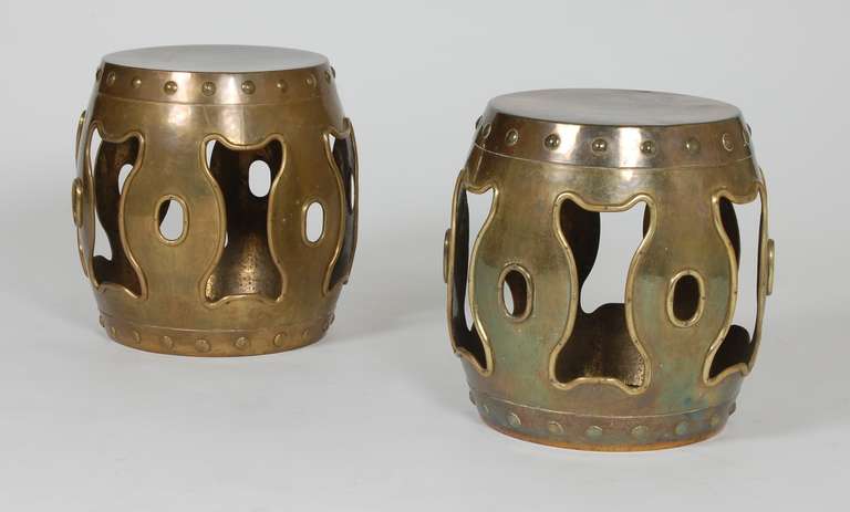 Pair of brass drum stools / tables in an Asian motif from Hong Kong circa 1970's.
 Brass trimming around the openings fastened with rivets, the finish has developed a great patina from over the years.