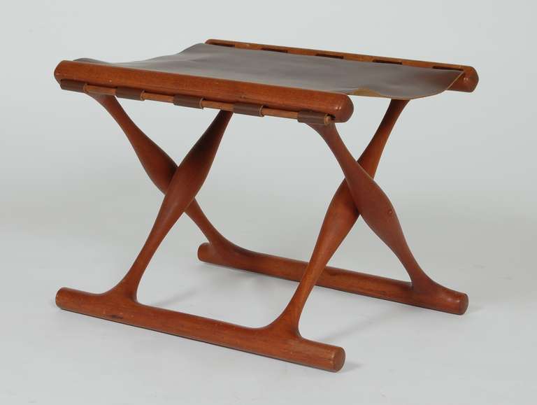 Folding teak stool by Danish designer Poul Hundevad. Leather top and a sculptural folding base of solid teak.