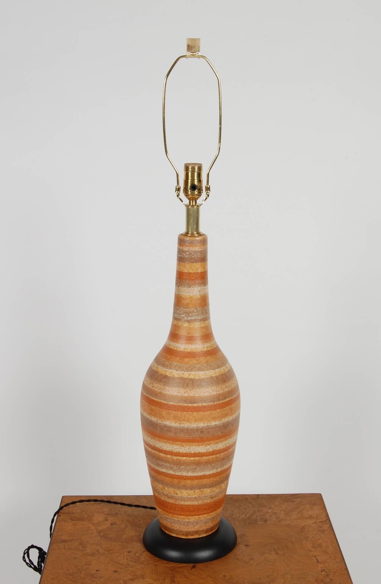 Striped ceramic lamp in various earth tone hues with a light volcanic glaze, black lacquer wood base all new electrical.