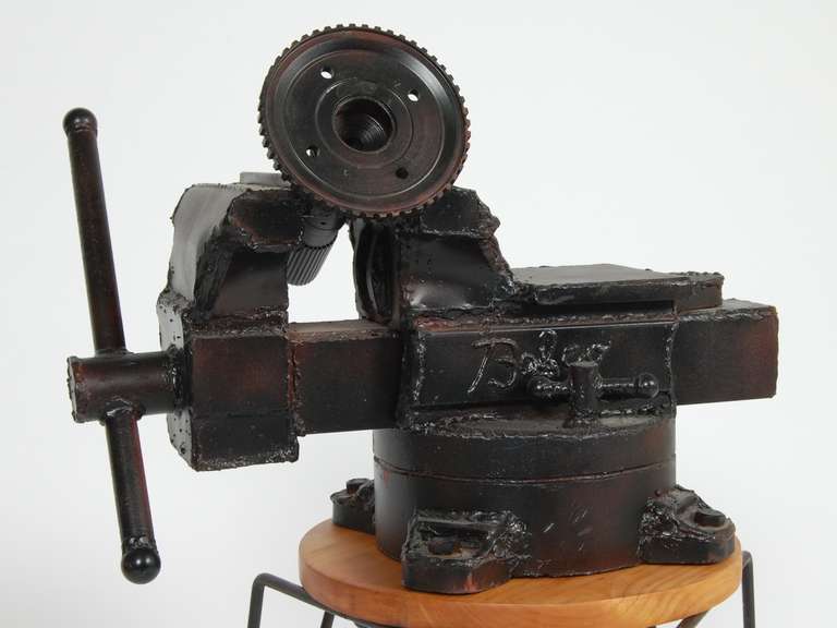 Welded steel sculpture of a vise holding a gear. This sculpture was a gift to the owner of Babco machine works in Oakland during the 1960s by the artist as thanks for Babco's help on a commission the artist was involved with. The piece is signed CP,