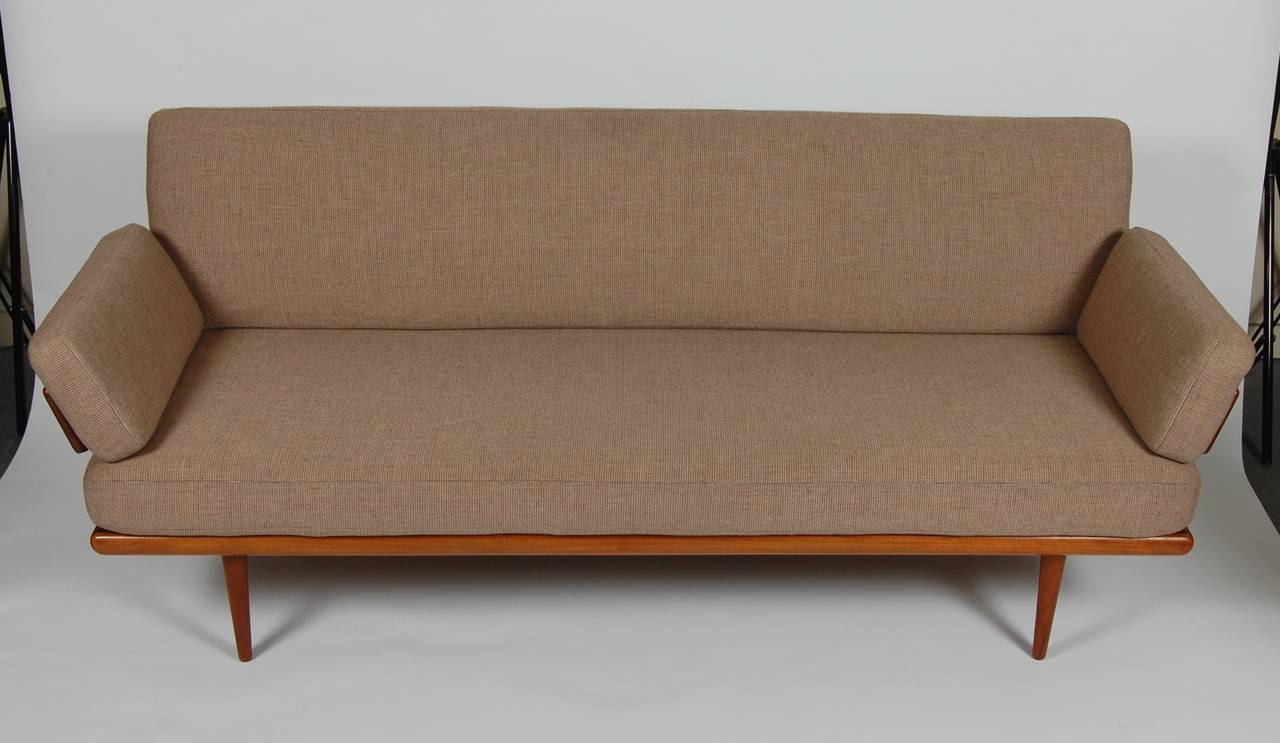 Sofa or daybed designed by Architect Peter Hvidt and Orla Molgaard-Nielsen of Denmark. Richly hued teak frame with chromed hardware accents and newly upholstered cushions. The paddle arms support the loose cushions which can double as pillows in