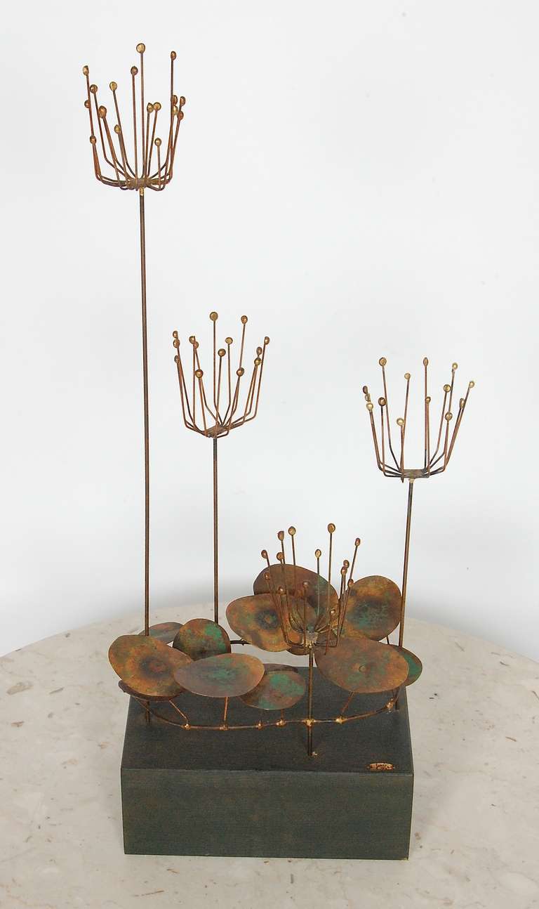 Engaging little table top sculpture by Jere dated 1968, one of the earlier designs from this studio. Other worldly plant forms created out of brass with an applied patina to the surfaces anchored on a wooden plinth. Tagged with a brass badge, signed