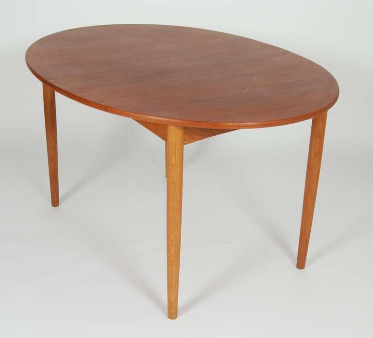 Compact oval Borge Mogensen dining table, teak top with oak legs, early 1950's production. The table expands from its 53