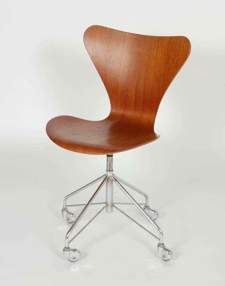 Arne Jacobsen Sevener swivel task chair model #3317, teak plywood seat with an adjustable height rolling  base, the range being from 16