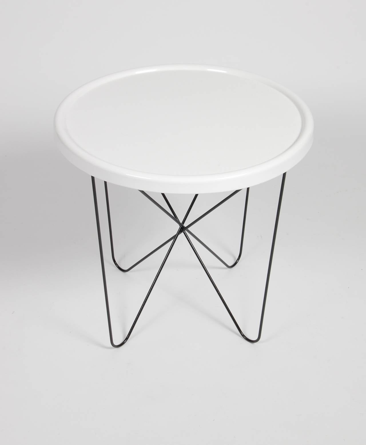 Circular white metal top patio table with black wire frame legs that can detach and fold for easy storage.