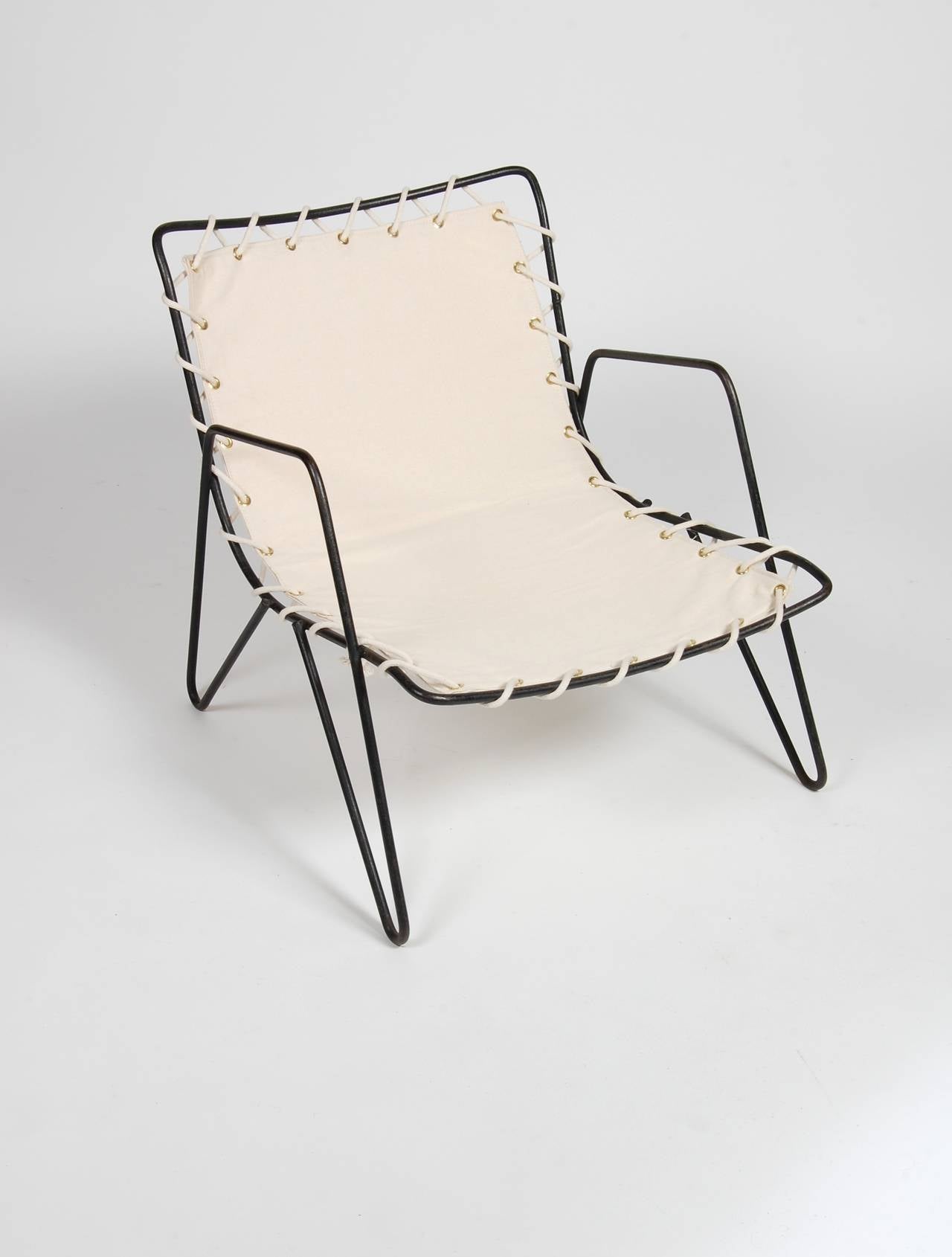 A very direct lounge chair design in period modernist patio furniture, having a curvy shaped seat attached to a soft hair pin leg to armrest form created out of rod iron. Covered in new canvas and attached via cotton yacht cord.