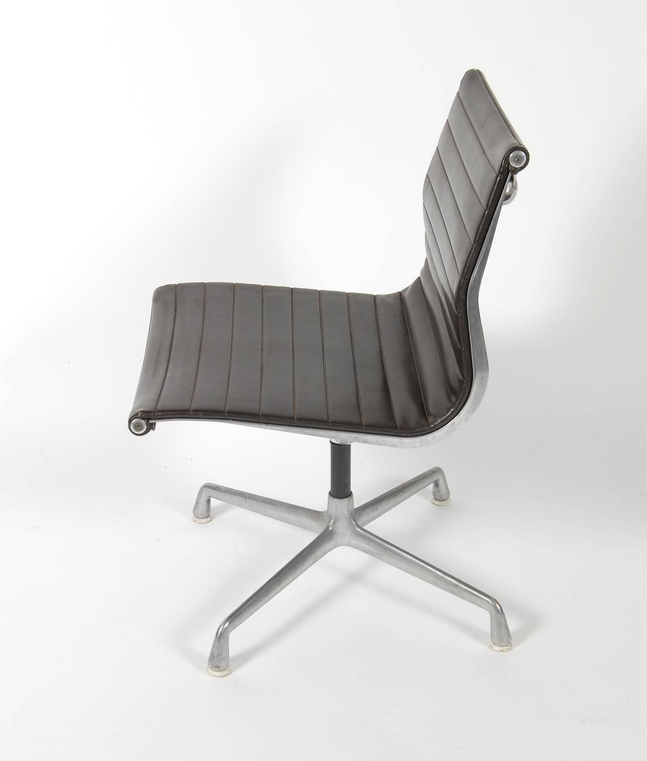 Aluminum Group swivel chair designed by Ray and Charles Eames. All original condition 1960s production chair with a four star swivel base with nylon glides and the sculptural aluminum frame upholstered in a dark brown vinyl. Marked with manufactures