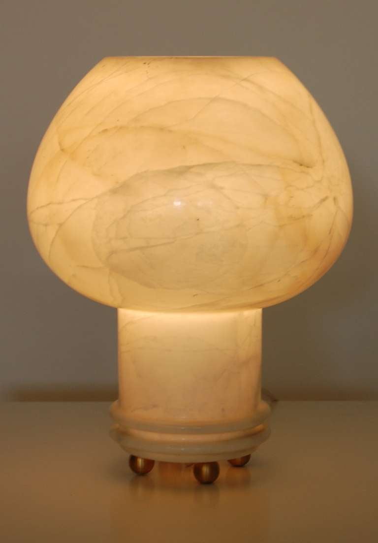 Accent table lamp rendered in alabaster, a striking goblet form with spheric brass feet. Rewired with an off white cloth covered cord and a two stage in-line switch. The alabaster has a translucent quality to it when illuminated creating a soft glow
