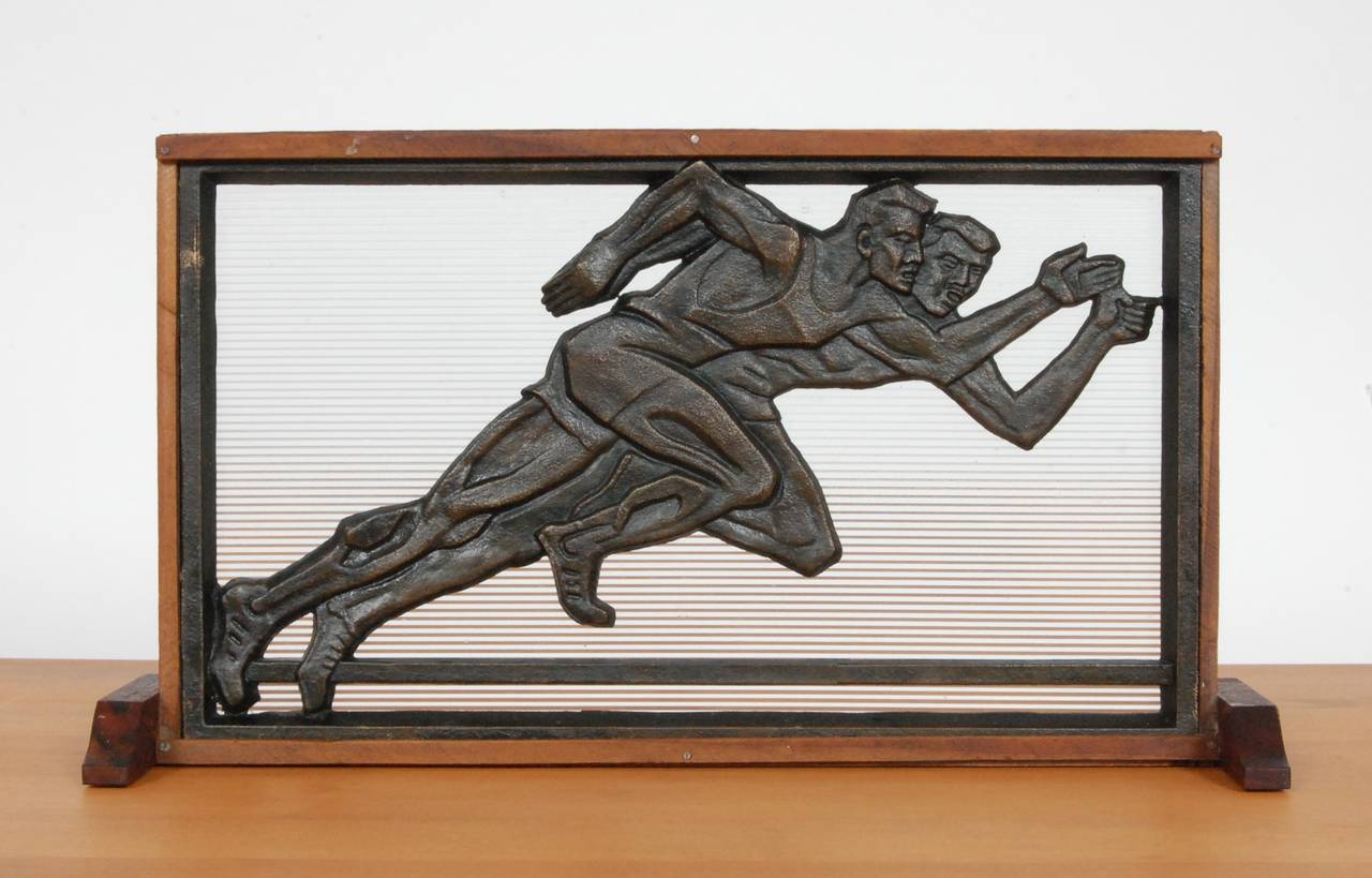 Bronze casting of two competing track runners with a lined glass backing. An architectural window element that has been framed for display.