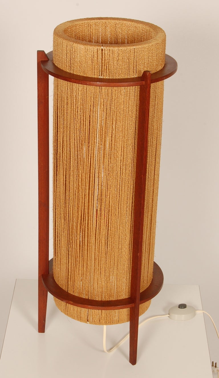60's era string and teak table or floor lamp from Denmark. The three legged teak frame has both circular and rectilinear forms with a double wrapped sisal cord shade over a wire subframe. 