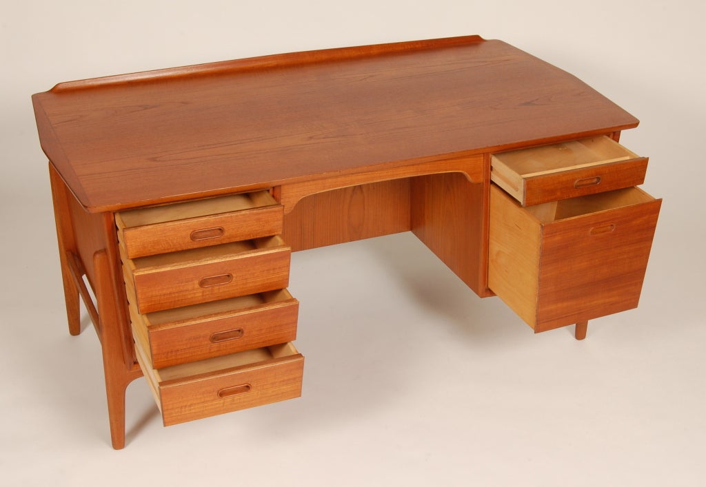 Teak Danish desk with a elongated hexagonal top, architectural exoskeletal legs, raised beveled back edge and tempered drawer front with a back shelf. Expressive graining to the teak, the large drawer on the right can be used for file storage and