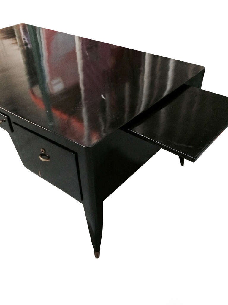A fine and important black lacquer bureau plat attributed to Dominique, circa 1935, with a pair of matching lacquered armchairs upholstered in black leather.  The desk has 3 drawers and two pill-out writing boards on slightly cabriolle legs with