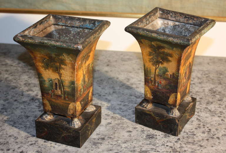 A pair of French Empire Period tole jardinaires, circa 1810, with bucolic scenes painted on all sides.