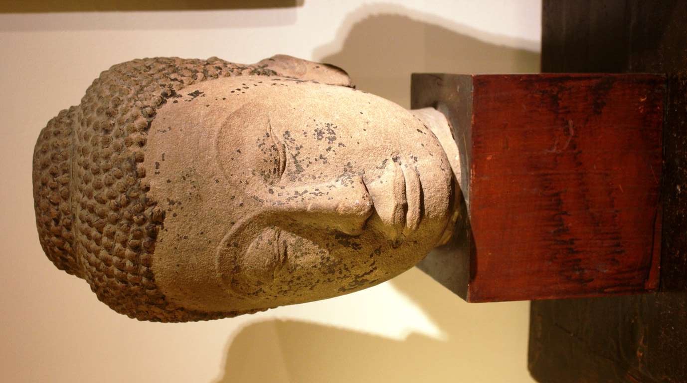 A large and beautiful Ayutthaya Style Buddha Head in sandstone, possibly 16th-17th century with traces of lacquer remaining, on a hand-hewn teak base.