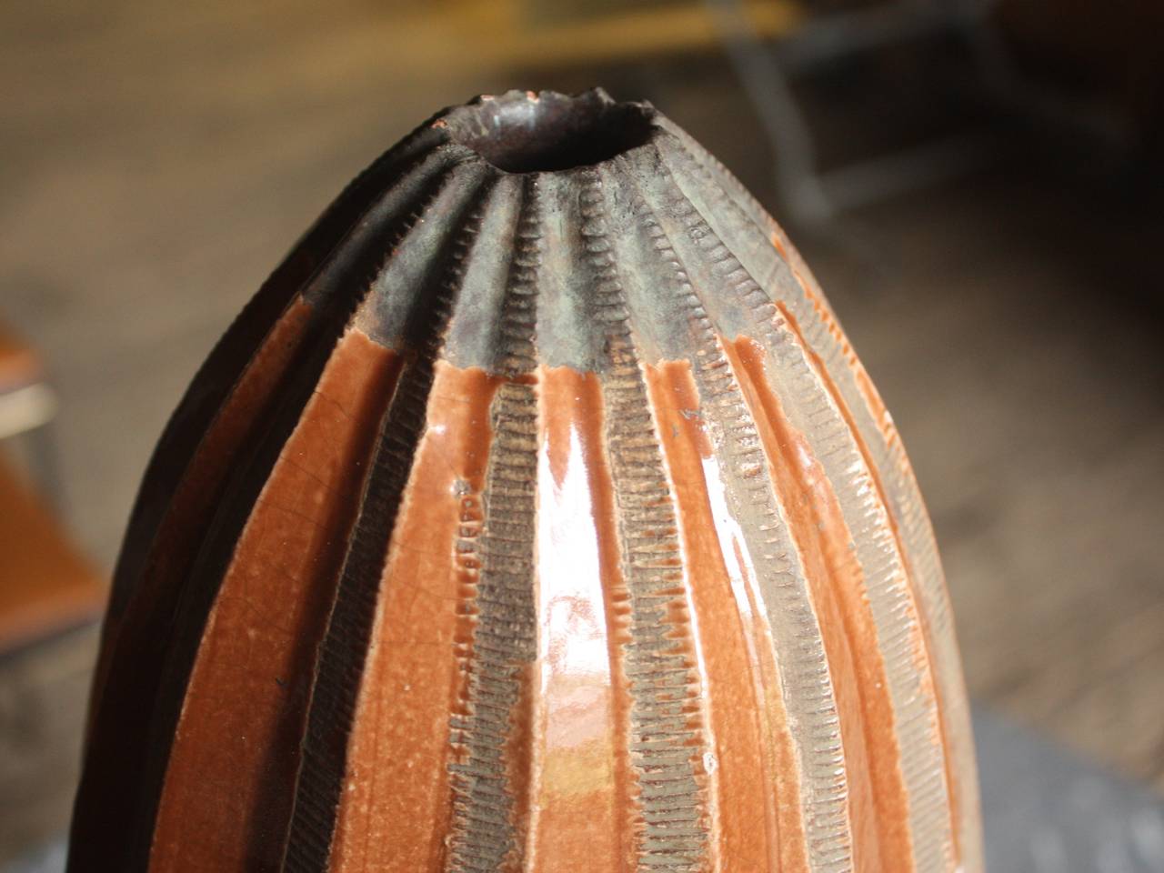 A large and unusual Art Deco period Studio Pottery vase in a ribbed torpedo form, with golden brown glaze and hand worked details, circa 1930.