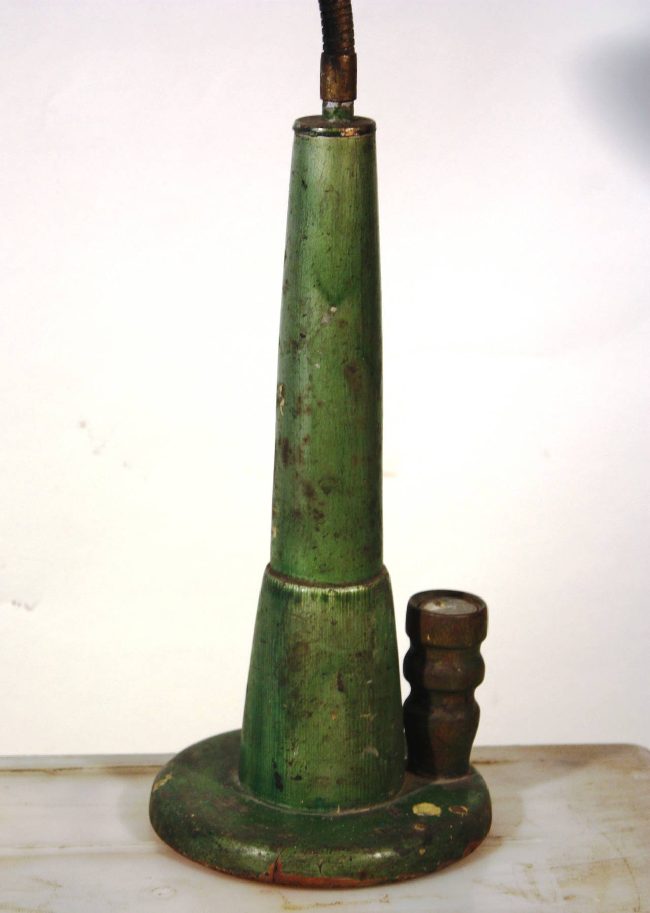 An interesting industrial table lamp circa 1930, with a turned wooden base and flexible steel neck, the base retaining its original green painted finish and tin shade.  Probably a tailor's lamp as the base has a small post which used to hold a pin