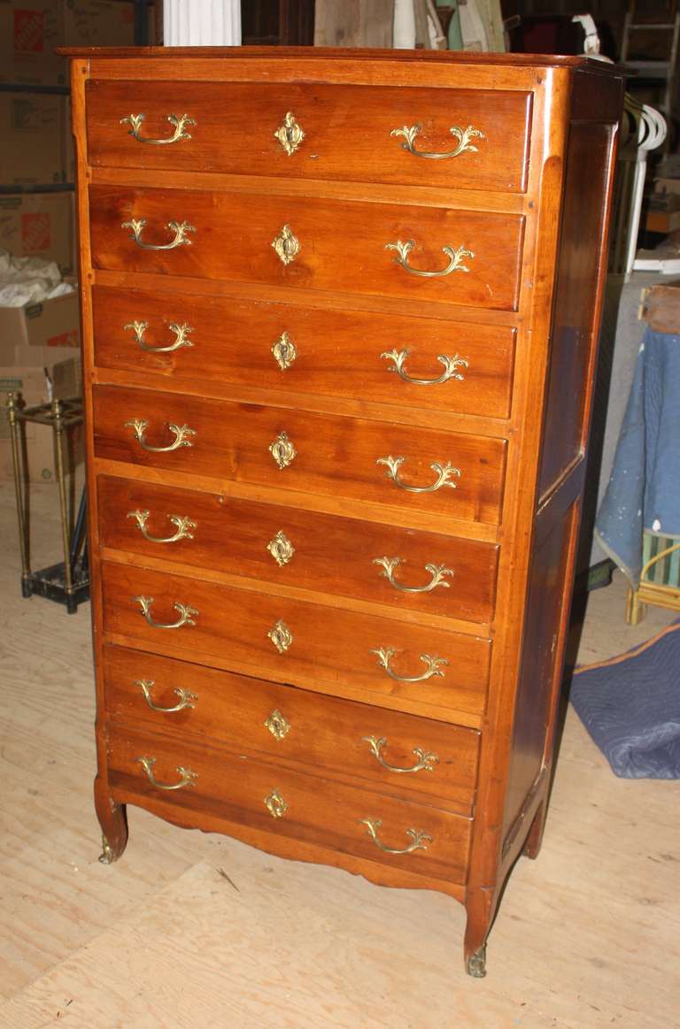 A Louis XV Style semainier (7 drawer chest) in walnut with 6 single upper drawers and a double height bottom drawer, with old brass drwaer pulls, key escutcheons and sabots, French circa 1860.