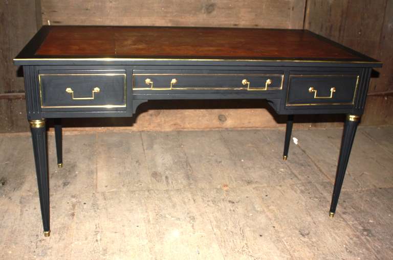 A very nice Louis XVI Style bureau plat in matte ebonized wood, with brass trim and mounts, retaining its original hardware and tooled brown leather top.  The desk is finished on the reverse and has 2 pull-out writing boards on each side.