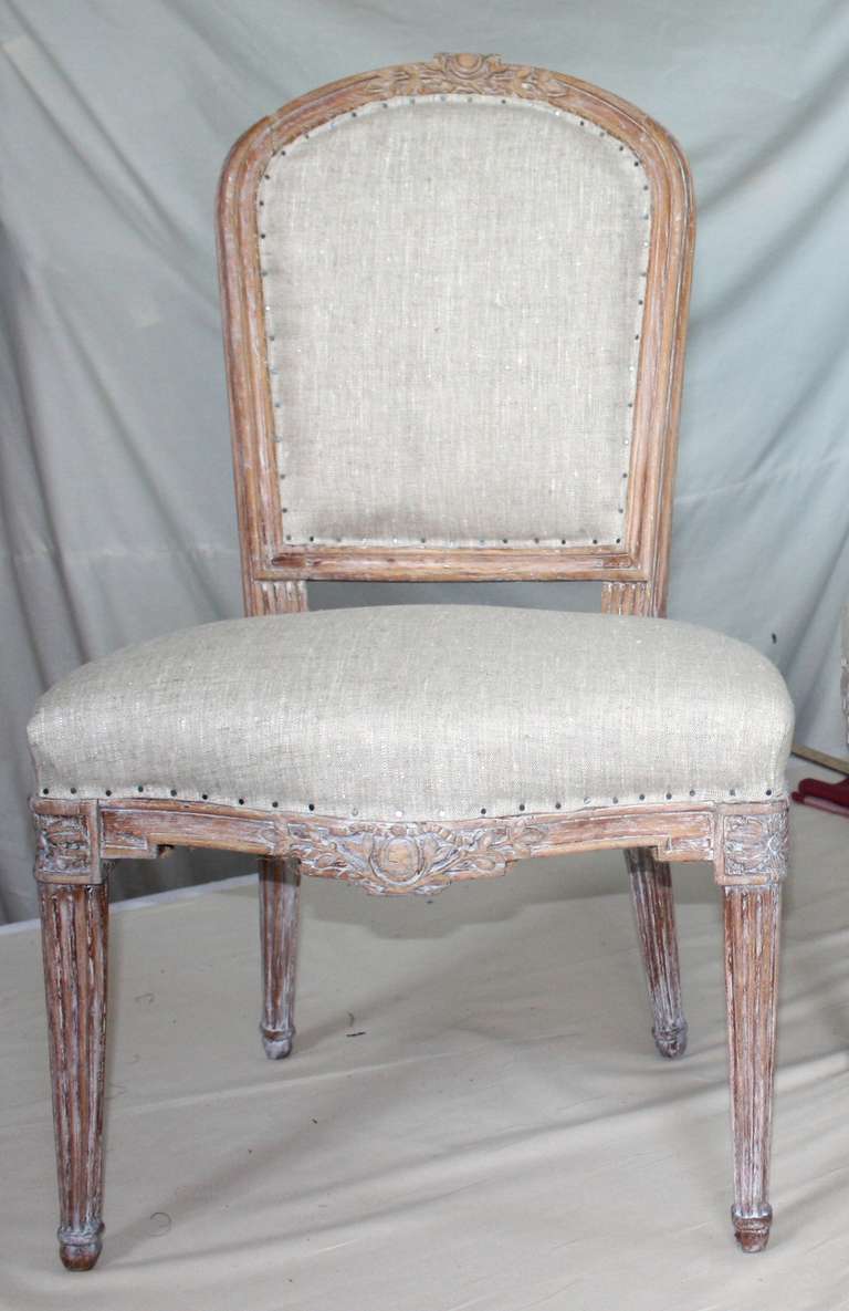 A very nice pair of French Louis XVI period side chairs in limed beechwood, circa 1780, the frames having fluted carvings on the legs and back with an arched back rail and seat rail carved with vines and flowers.  Nice larger scale for 20th century