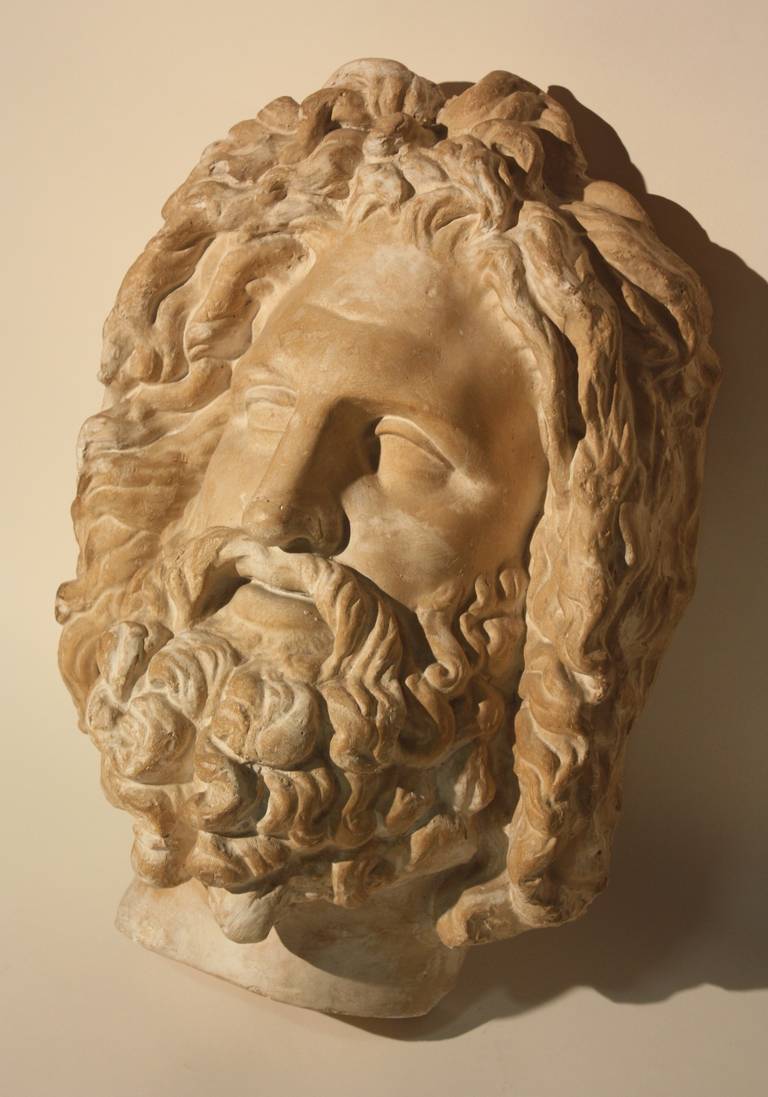 A very large mask or half bust of Zeus in plaster, designed to hang flush on a wall, circa 1940, possibly French, with a nice patina.