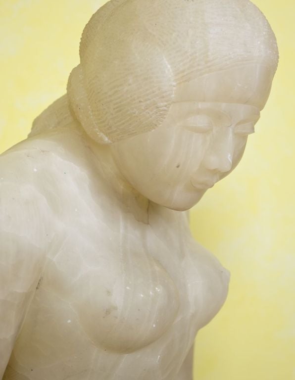 A large carved alabaster sculpture of a seated Asian woman, in the manner of William Zorach, with a custom faux marble painted wooden base, circa 1930.
