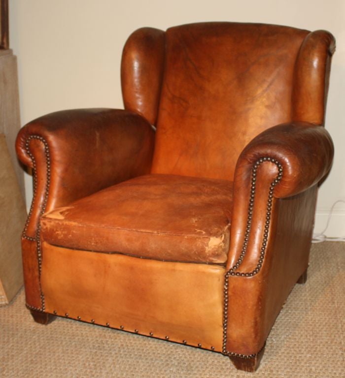 A really nice pair of leather club chairs, French, circa 1930, with rolled arms and wing backs.  The leather is worn just right and the down-stuffed seat cushions have leather on one side and brown velvet on the reverse.