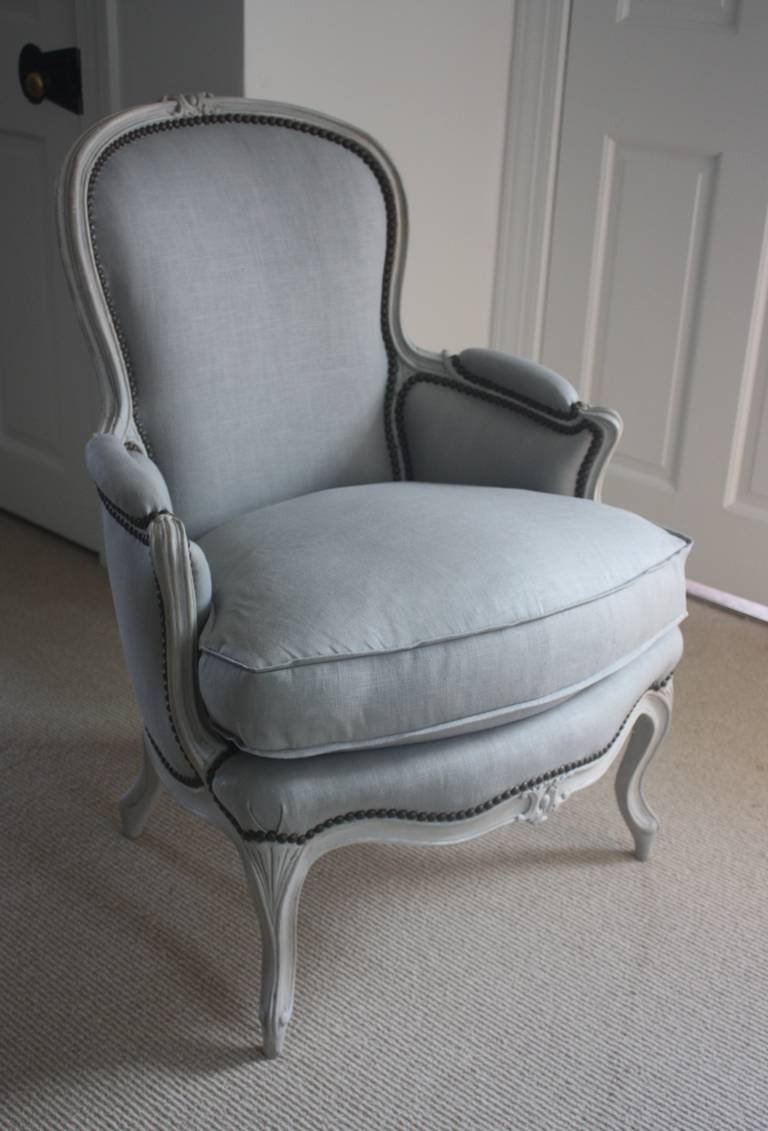 A beautiful Louis XV style bergère chair, circa 1890, the frame with cabriole legs and nicely carved crest and seat rail, painted in pale grey or blue finish. The chair is newly upholstered in a pale blue linen fabric with patinated nailheads. The