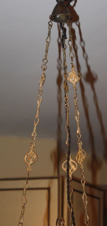 A chic hanging lantern, probably Moroccan, circa 1920, in pierced brass with colored glass panes.  The lantern hangs on three decorative chains and has been recently electrified.