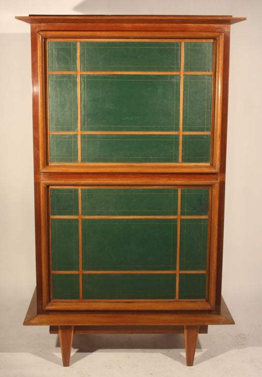 A rare and unusual double bar cabinet in light mahogany with green leather inset panels on facade, the upper and lower doors revolve to expose a cream lacquered fitted interior with glass shelf and bottle holders.
