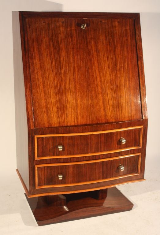A fine French slant-front bureau secretaire in rosewood veneer with sycamore trim and interior.   The case has great proportions with a generous writing surface.  The drawer fronts are slightly serpentine and the base is composed of an open circular