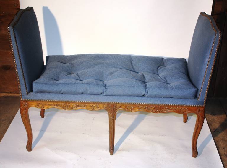 A charming French Louis XV carved and upholstered 2-seat window bench with cabrilole legs, high arched arms and a loose cushion.  The fruit-wood frame is nicely carved on all sides.  Late 19th, early 20th century.