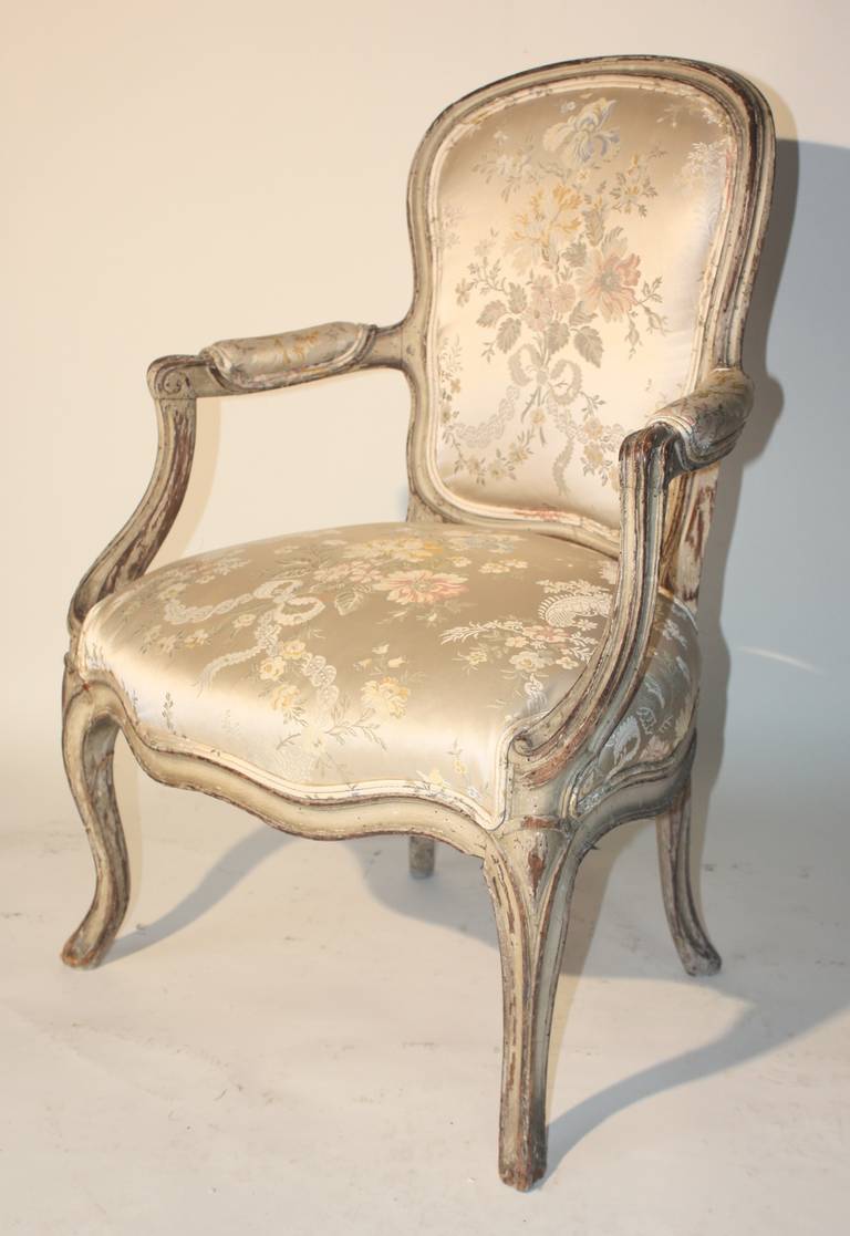 A diminutive Louis XV period fauteuil cabriolet, circa 1760, in distressed grey painted finish, nicely sculpted and perfect proportions, currently upholstered in a silk damask fabric.